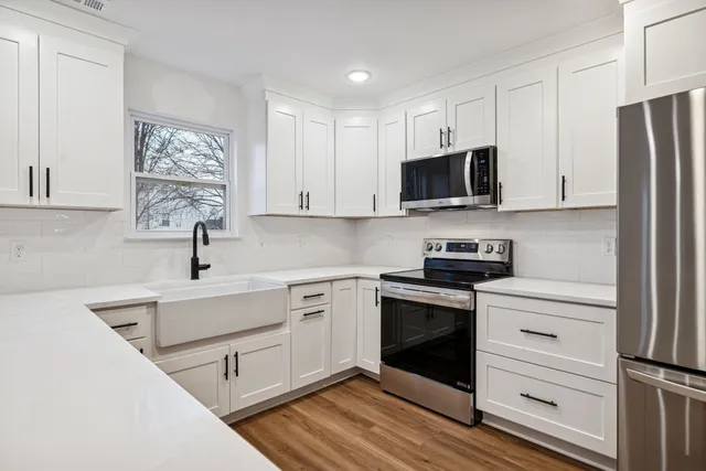 a kitchen with a sink white cabinets and stainless steel appliances