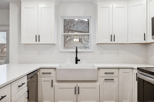 a kitchen with a sink dishwasher a stove and white cabinets with wooden floor