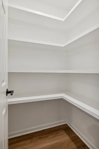 a spacious bedroom with a bed and wooden floor