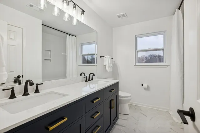 a view of a hallway with wooden floor and a bathroom