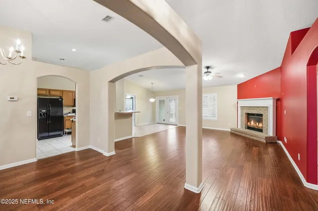 a view of an empty room with wooden floor and a fireplace