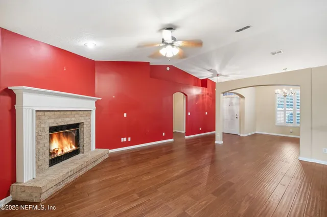 a view of an empty room with wooden floor fireplace and a window