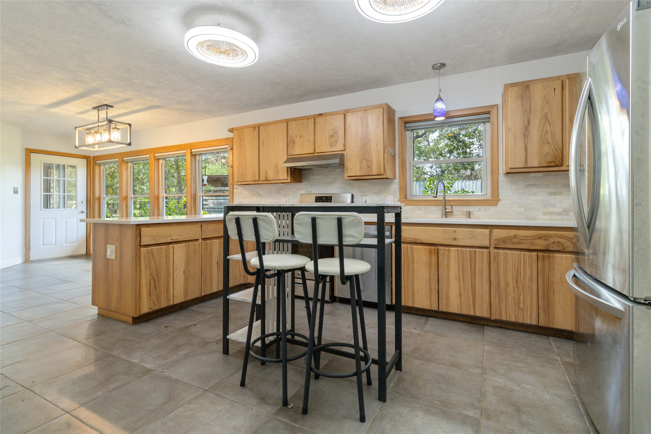 180 Ironstone Road Smithville, TX 78957 - Photo 26 of 37 Kitchen featuring freestanding refrigerator, hanging light fixtures, light countertops, and tasteful backsplash