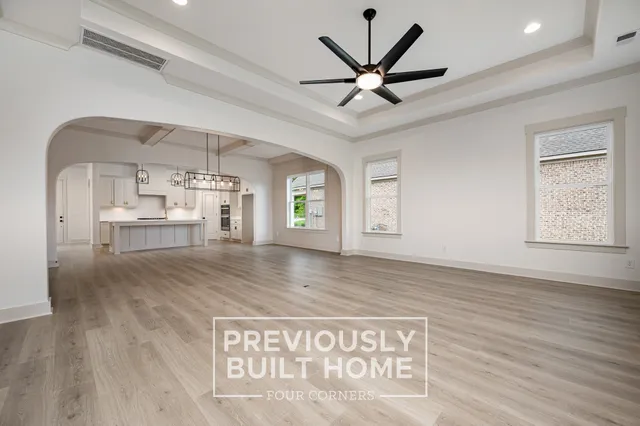 a view of a hallway with wooden floor and a ceiling fan