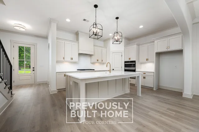 a kitchen with kitchen island granite countertop a sink cabinets and wooden floor
