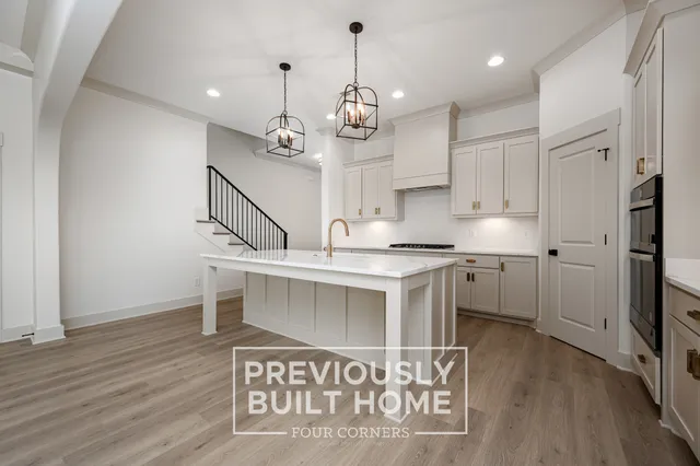 a kitchen with kitchen island granite countertop a sink cabinets and wooden floor