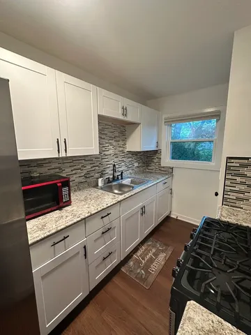 a kitchen with granite countertop a sink stove and cabinets