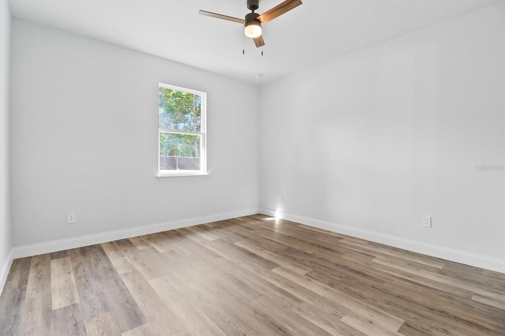 6716 East Crimson Lane Inverness, FL 34452 - Photo 21 of 44 an empty room with wooden floor ceiling fan and windows