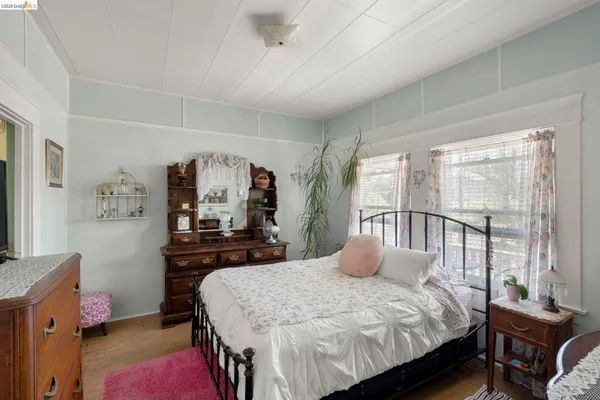 a bedroom with a bed a large window with table and chair