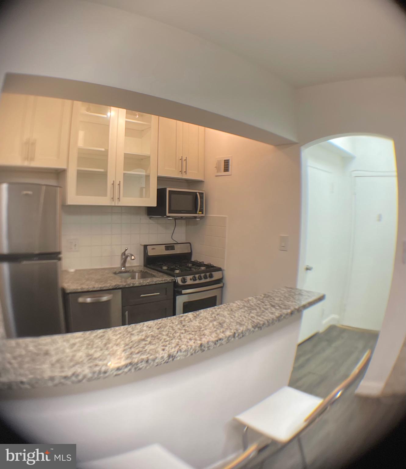 1 Scott Circle Northwest, Unit 118 Washington, DC 20005 - Photo 16 of 35 a kitchen with granite countertop a stove a sink and a microwave
