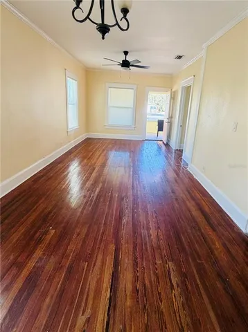 a view of empty room with wooden floor and fan