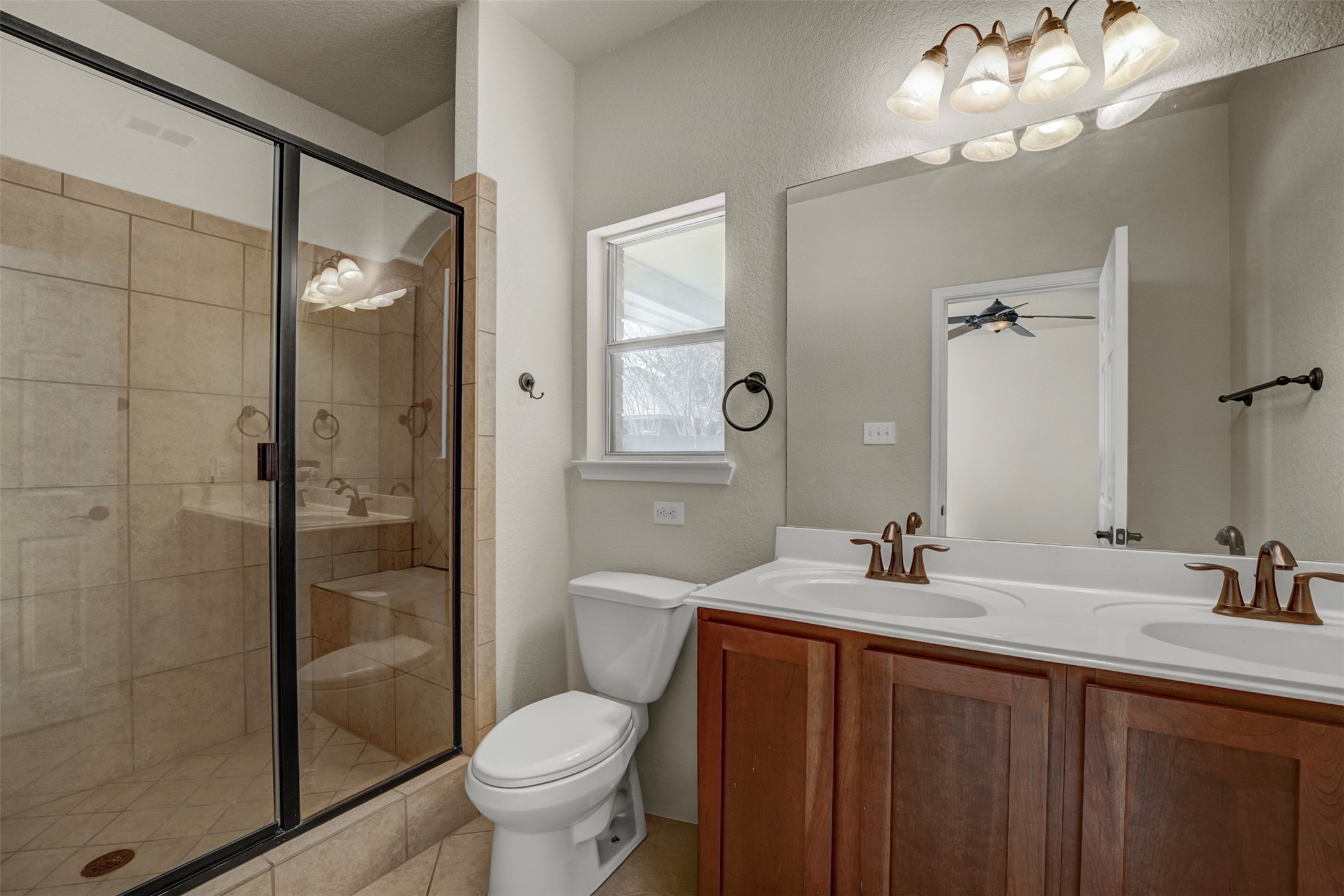 10506 Corvey Lane Helotes, TX 78023 - Photo 14 of 28 Full bathroom featuring double vanity, a stall shower, and a ceiling fan