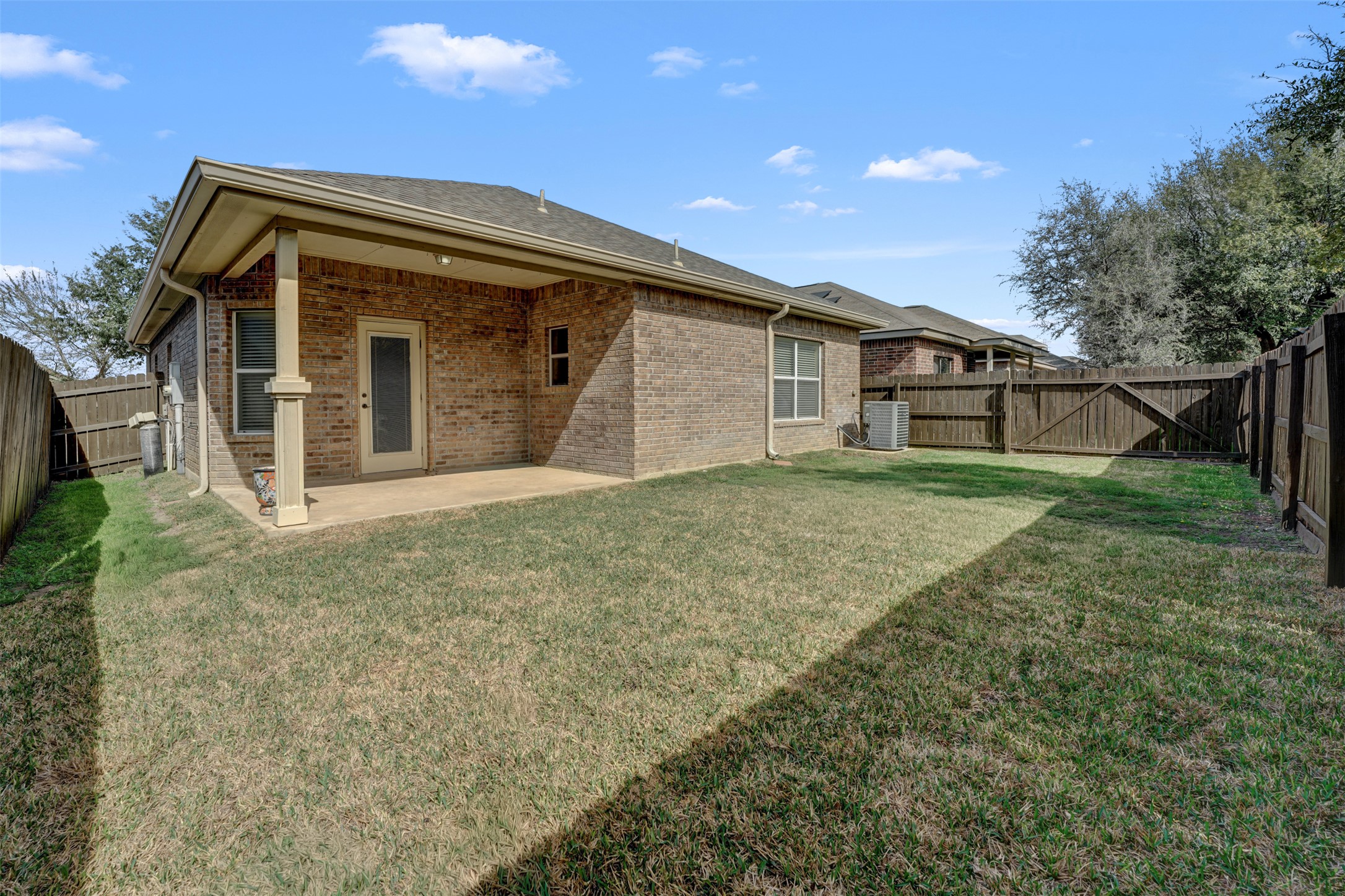 10506 Corvey Lane Helotes, TX 78023 - Photo 23 of 28 Back of property featuring a patio, brick siding, a fenced backyard, and a gate