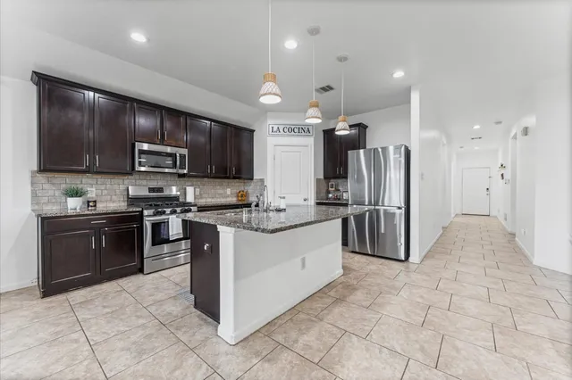 a kitchen with stainless steel appliances granite countertop a refrigerator and a stove top oven