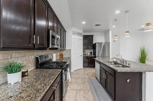 a kitchen with stainless steel appliances granite countertop a sink a stove and a wooden floors