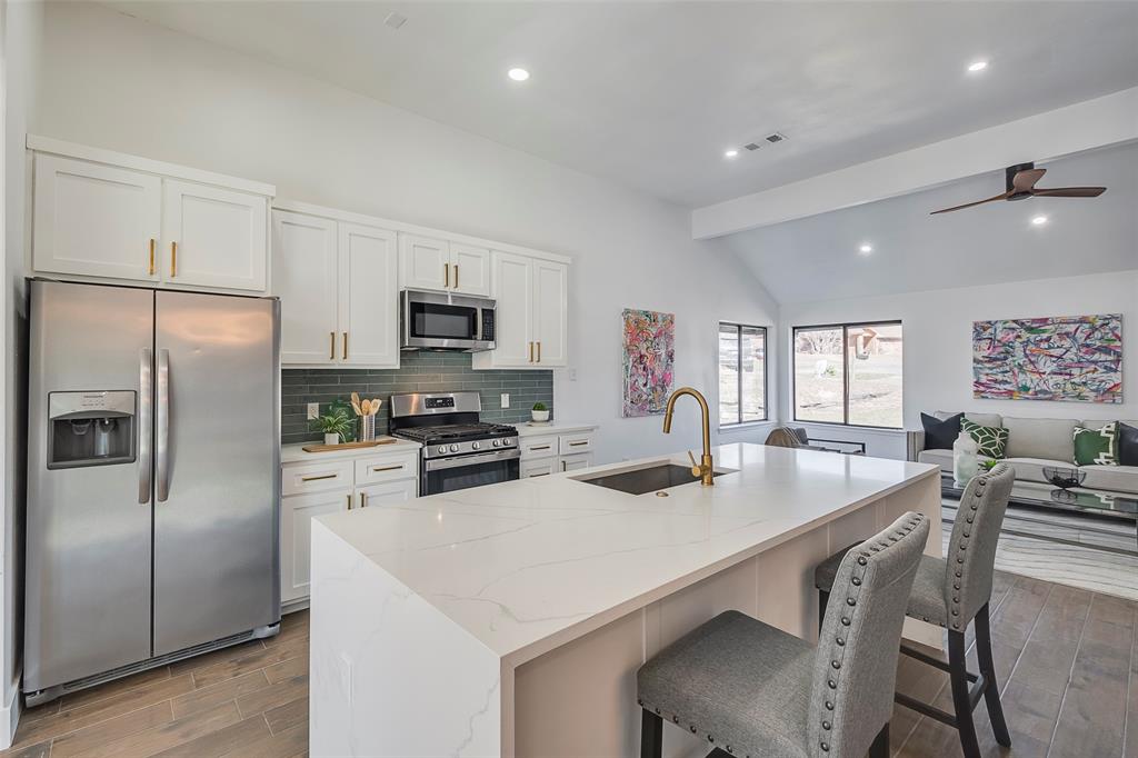 5607 Emrose Circle Dallas, TX 75227 - Photo 9 of 25 a kitchen with stainless steel appliances a table chairs microwave and refrigerator