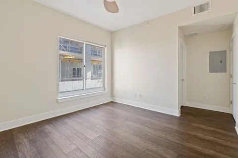a view of an empty room with wooden floor and a window