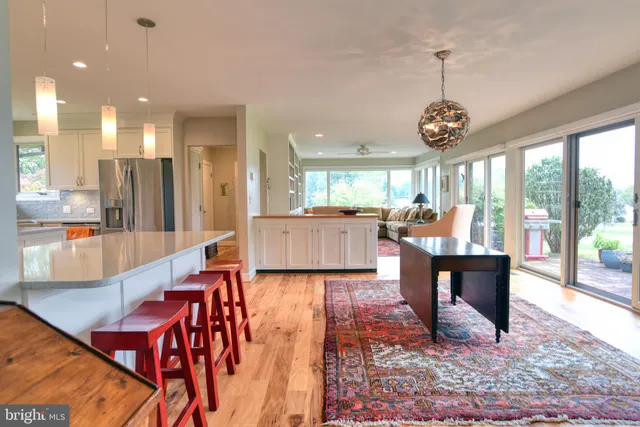 a view of a dining room and livingroom with furniture wooden floor a chandelier