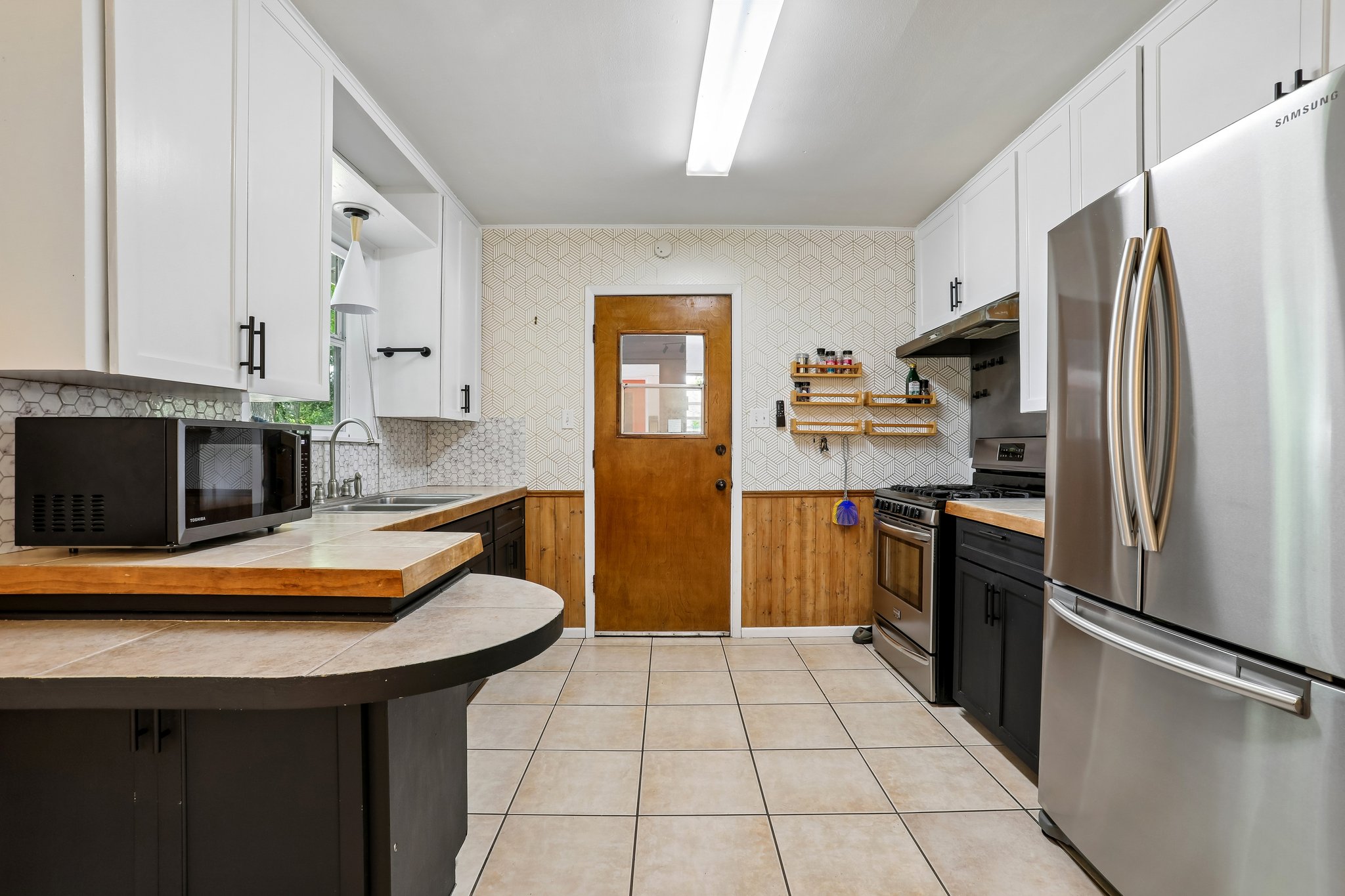 1114 West 2nd Street Elgin, TX 78621 - Photo 7 of 31 A functional kitchen features sleek stainless steel appliances and abundant cabinetry, perfect for culinary endeavors.