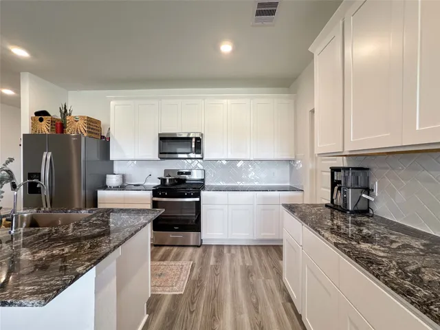 a kitchen with stainless steel appliances granite countertop a sink stove microwave and refrigerator