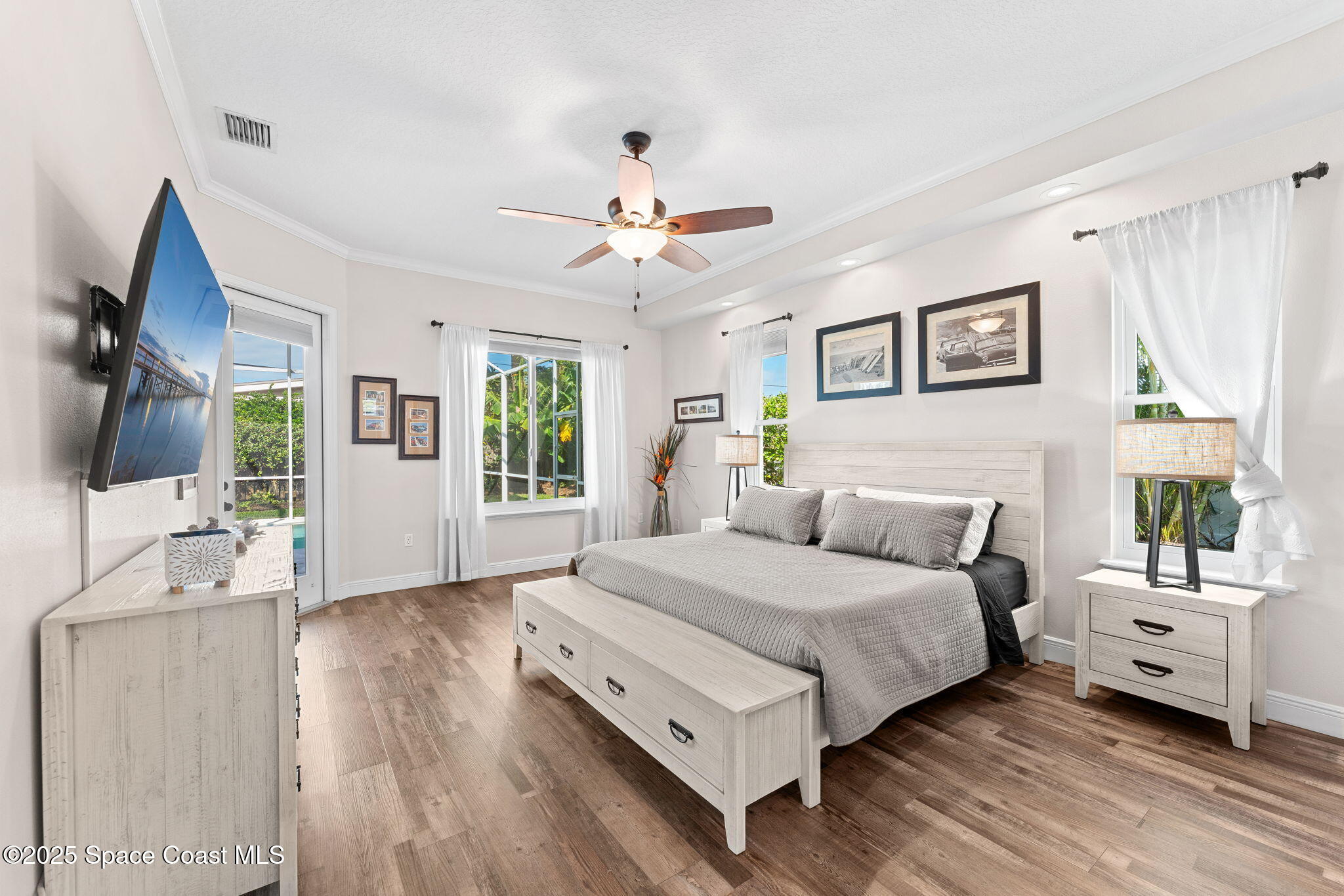 162 Miami Avenue Indialantic, FL 32903 - Photo 16 of 49 a bedroom with a large bed a flat tv screen and a chandelier