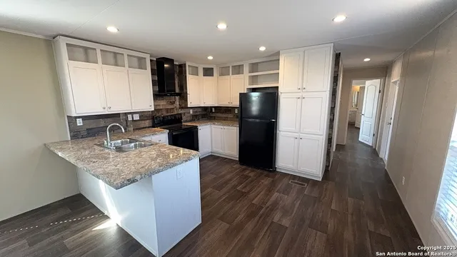 a kitchen with stainless steel appliances granite countertop a refrigerator a sink a stove and wooden floors