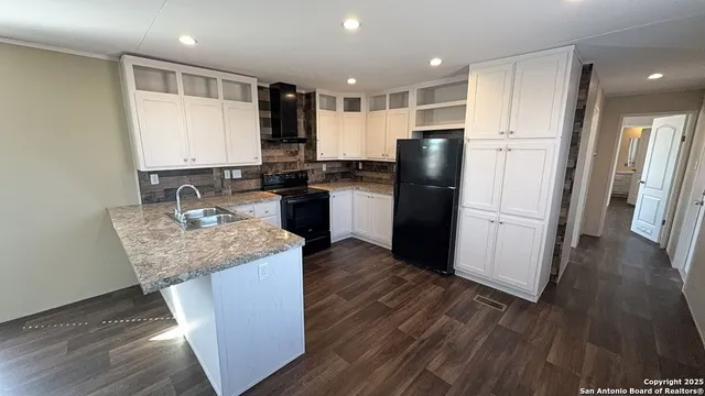 a kitchen with stainless steel appliances granite countertop a refrigerator a sink a stove and wooden floor