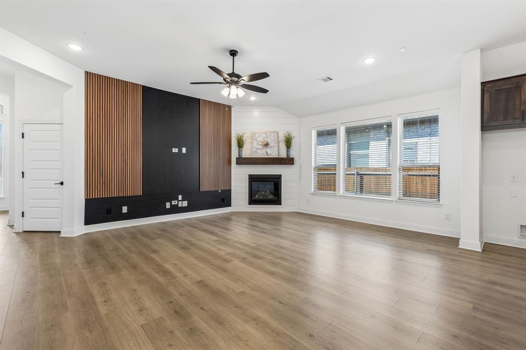 5224 Troupe Road McKinney, TX 75071 - Photo 8 of 31 Wood-finish flooring throughout, modern media wall with wood slat accents, corner fireplace with a wood mantle, white shiplap wall detail, and recessed lighting