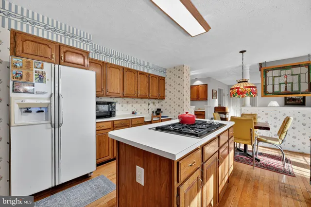 a kitchen with stainless steel appliances a stove a refrigerator a sink dishwasher and a dining table with wooden floor