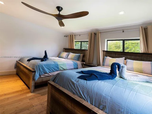 a bedroom with two beds and a flat tv screen on dresser