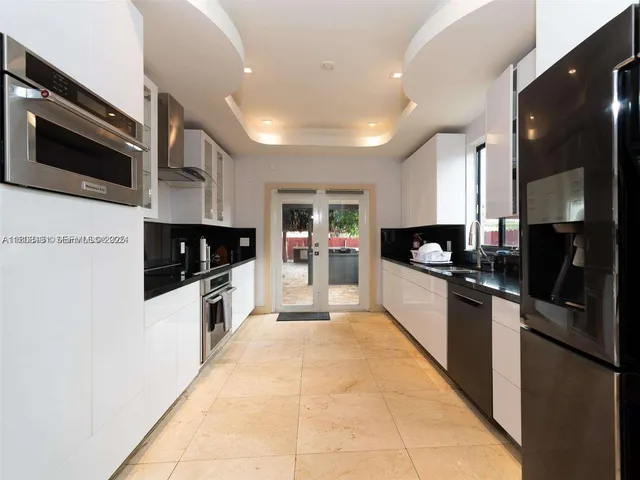 a large kitchen with stainless steel appliances kitchen island granite countertop a refrigerator and a stove top oven