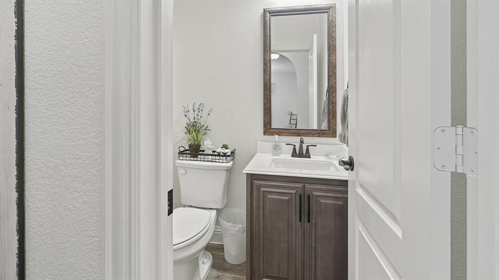 5216 Troupe Road McKinney, TX 75071 - Photo 40 of 40 Powder room featuring a single vanity with a white countertop, dark wood-finish cabinetry, matte black hardware, and a framed mirror