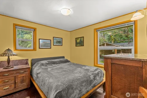 a bedroom with a bed and a dresser next to a window