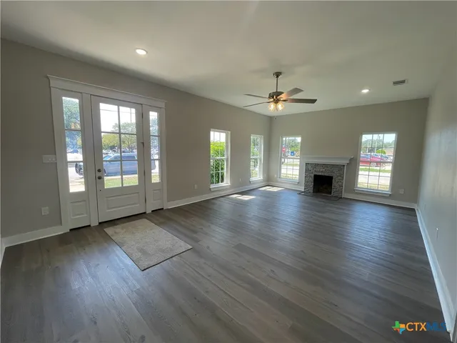 a view of an empty room with window and wooden floor