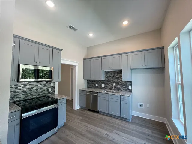 a kitchen with stainless steel appliances kitchen island granite countertop a stove and a refrigerator