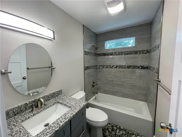 a bathroom with a granite countertop sink a toilet and bathtub