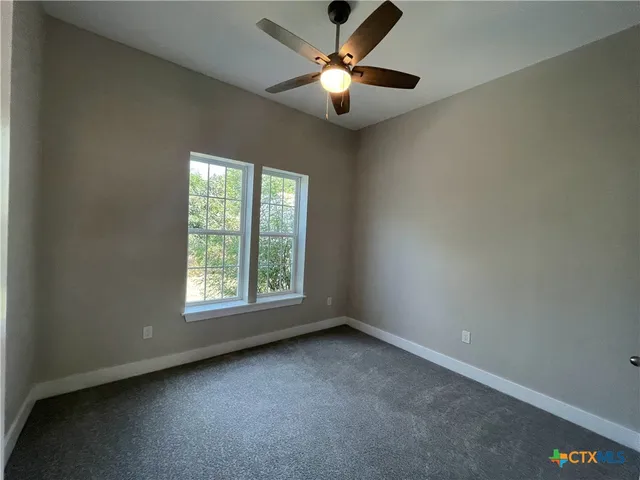 an empty room with a window and a fan