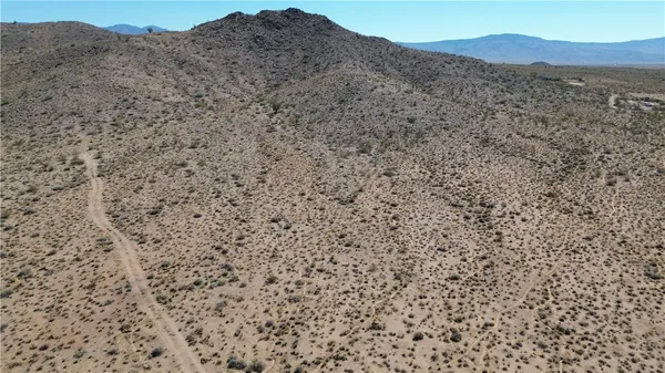 a view of a dry field with mountains in the background