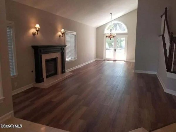 an empty room with wooden floor fan and window