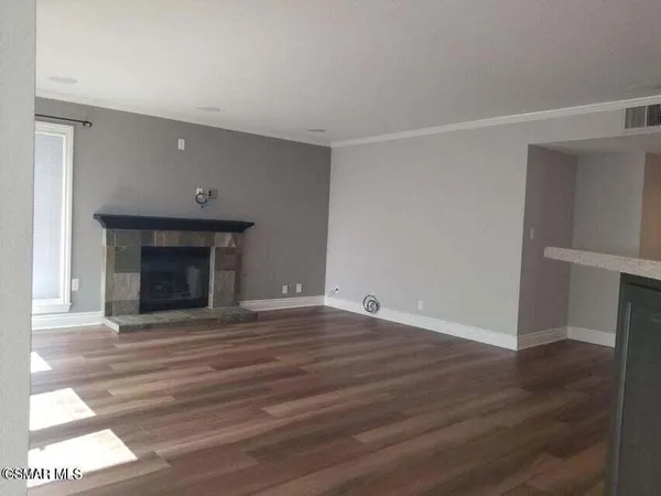 a view of empty room with wooden floor and fireplace