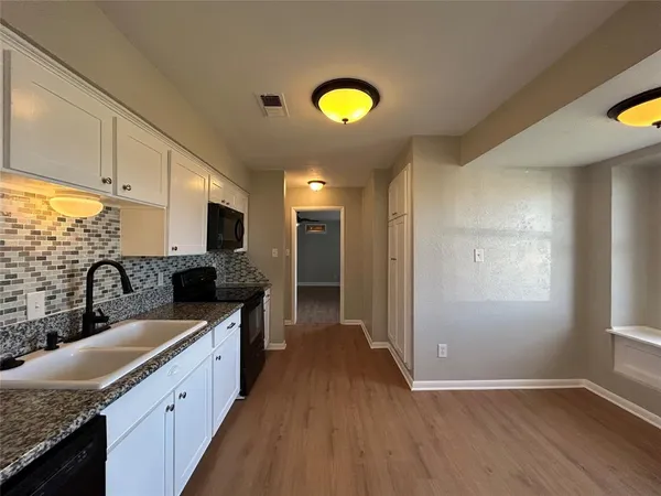a kitchen with granite countertop a sink appliances counter top space and cabinets