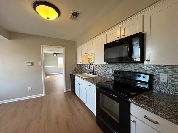 a kitchen with granite countertop a stove and a wooden floor