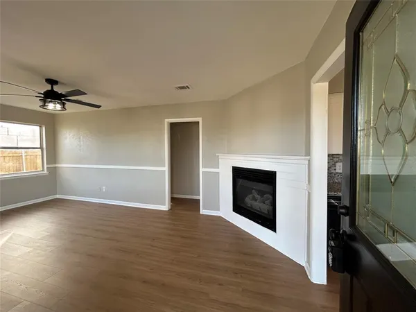 an empty room with wooden floor fireplace and windows