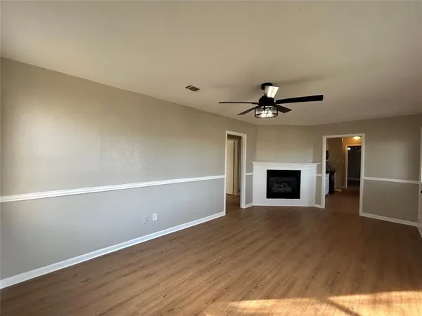 a view of an empty room with wooden floor fireplace and a window