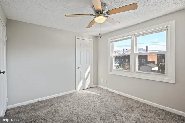 an empty room with windows and fan