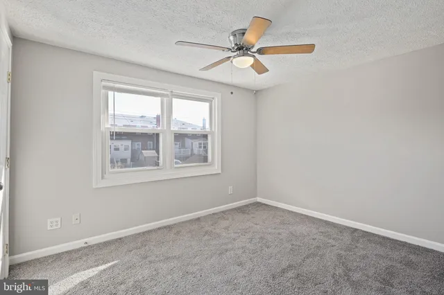 an empty room with a window and a fan