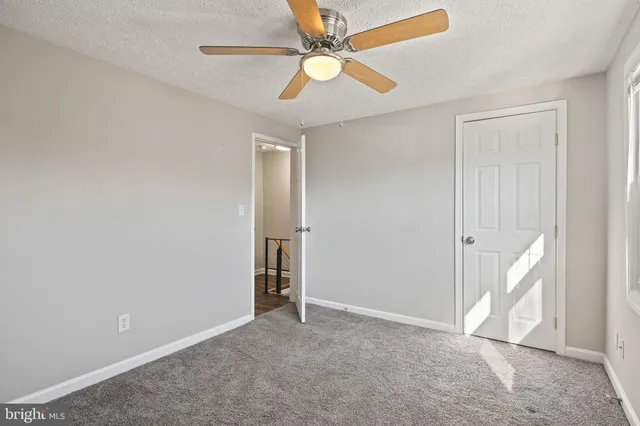 an empty room with closet and a ceiling fan