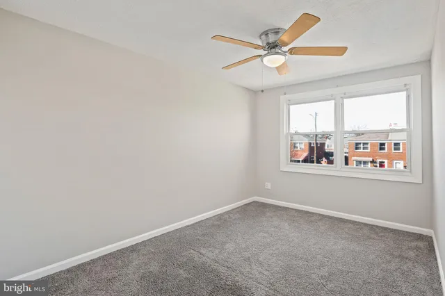 an empty room with a window and a ceiling fan