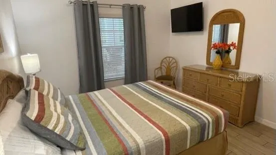 a bedroom with a bed and a flat tv screen on dresser
