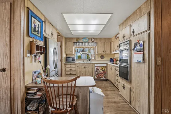 a kitchen with stainless steel appliances a refrigerator a stove a sink dishwasher and white cabinets with wooden floor